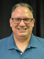 Brad Stanton, a smiling, caucasian, middle-aged man with short brown and gray hair, wearing glasses and a blue shirt.