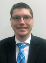 Jeremy Smith, a smiling young white man wearing a suit with a blue patterned tie and white collared shirt.