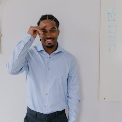 man in a button-up shirt smiling with his hand to his head