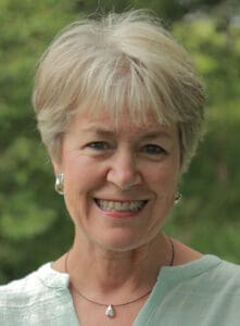 photo of Juliette Perkins, female presenting with short, grey-blond hair and a light blue notch collar shirt