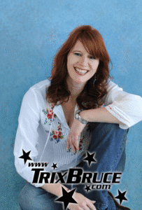 photo of Trix Bruce, female presenting with shoulder length red hair, a white 3/4 length sleeve shirt and blue jeans. and an overlay of her website www.trixbruce.com